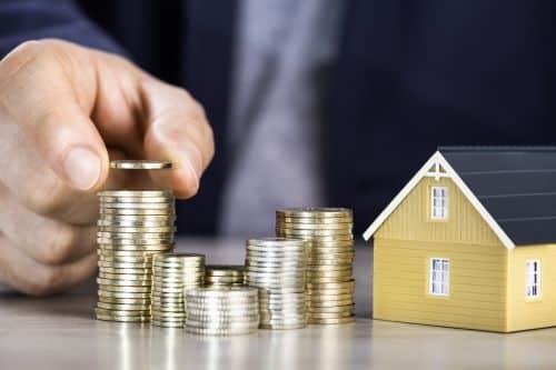 stacked coins next to a house