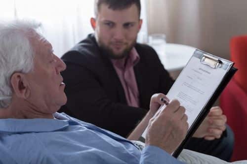 an elder man signing paperwork 