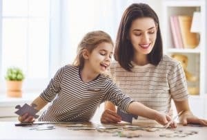 a mother doing a puzzle with her daughter.
