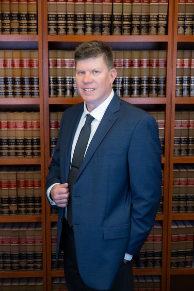 James Fraser in a suit standing in front of bookshelf